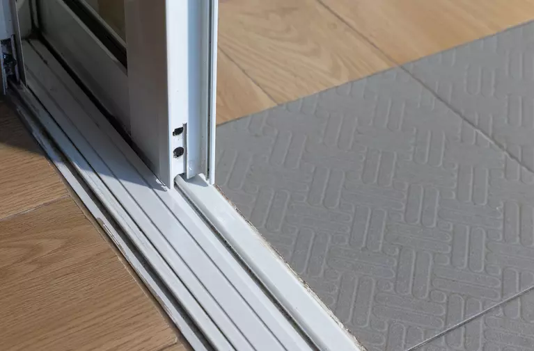 A closeup of the metal tracks beneath a sliding glass exterior door.
