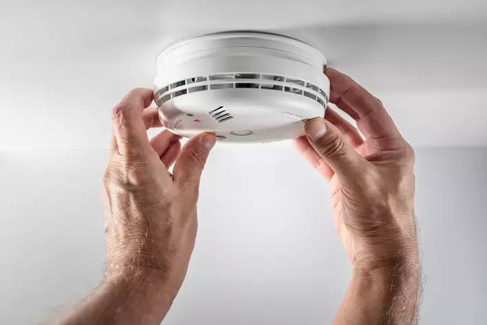 Man replacing batteries in a smoke detector in a home