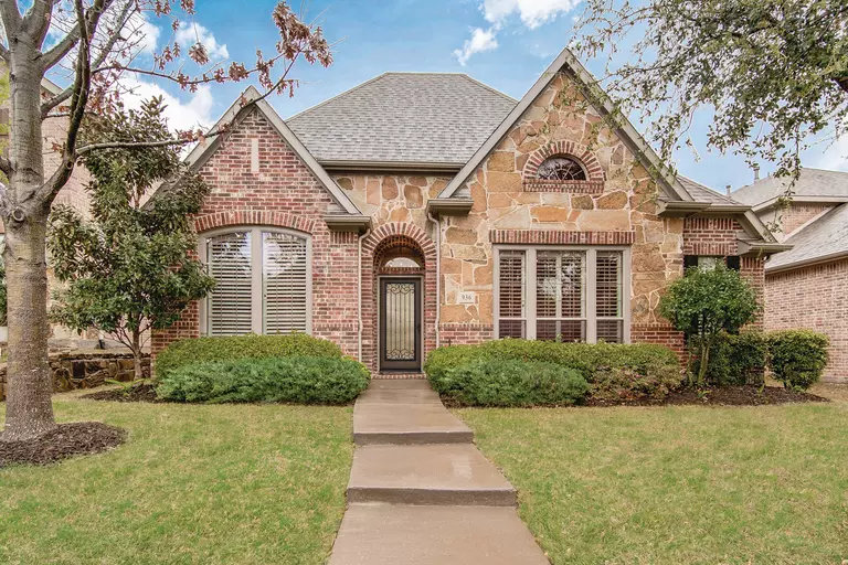 A stone and brick home with a large front yard and renovated landscaping to enhance curb appeal.
