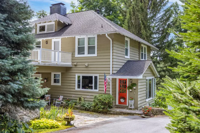 Exterior of a two-story home in a wooded area with light gray vinyl siding.