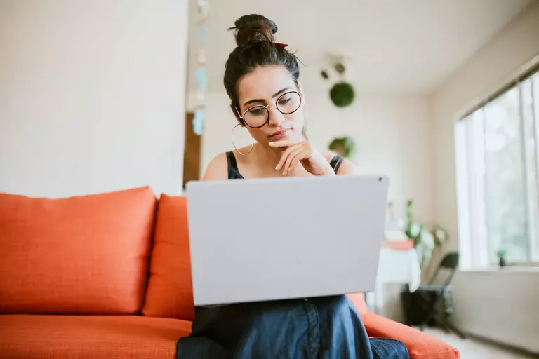 Woman working online on a laptop in the comfort of her home.