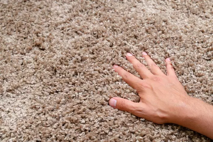Close-up of a hand touching a soft carpet. Gentle and fluffy carpet between fingers.