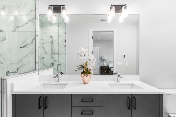 A modern white bathroom with marble tile and white countertops