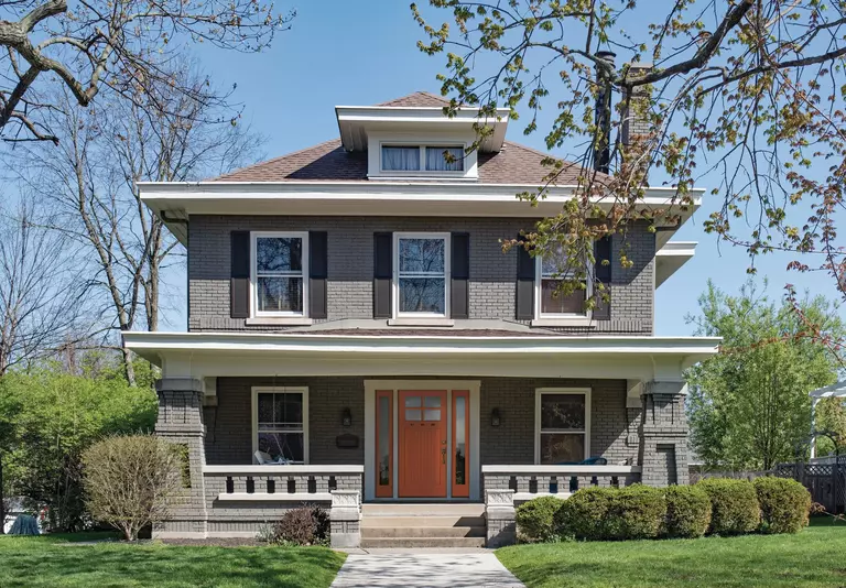 A large house with a red door and replacement windows, along with a well-kept lawn