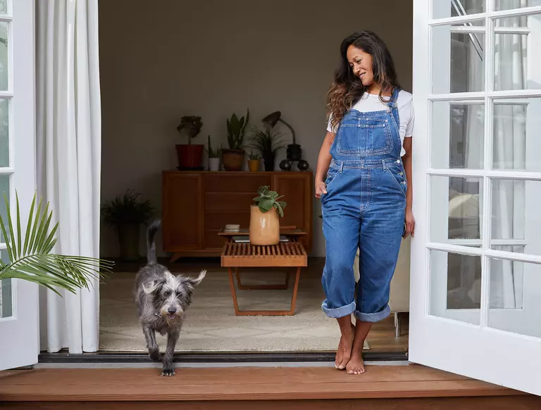 Smiling woman and dog hanging out on patio with patio doors open.