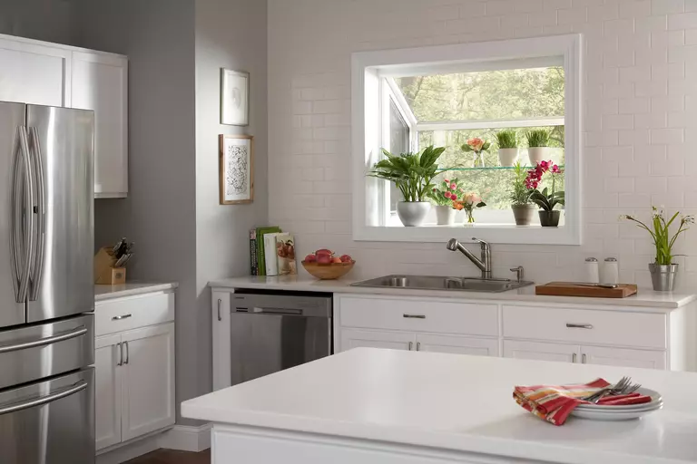 White garden window with plants and herbs placed in front.