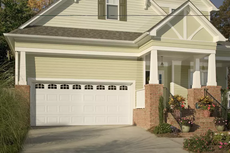 Front of a home with a white garage door and a brick porch.
