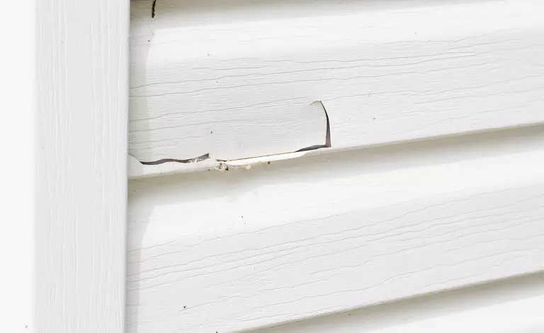 A crack in the white exterior siding of a home.