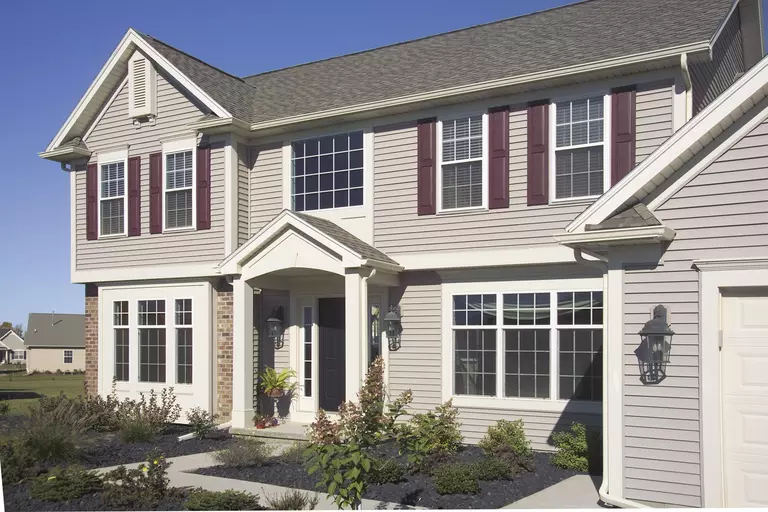 Exterior of a two-story home with light gray vinyl siding and brick.