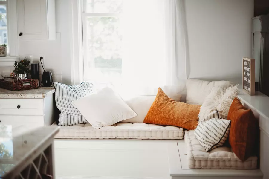 A cozy kitchen nook with pillows next to a bright window