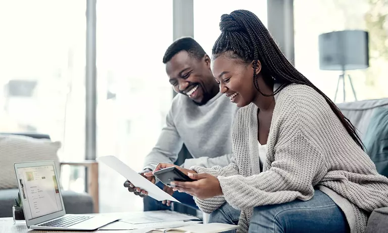 Couple sitting on a couch together, marking their energy-efficient windows as a tax deduction. 