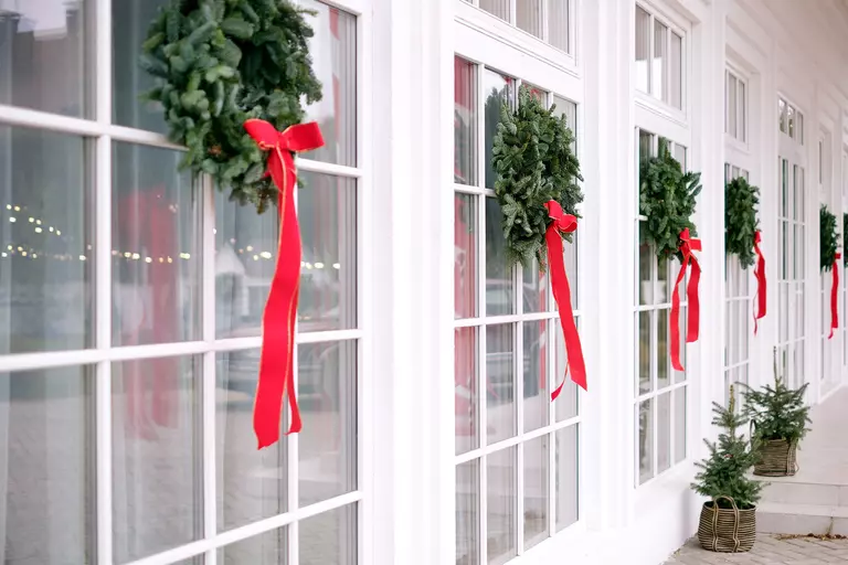 The exterior of a residence with multiple wreaths on a row of windows.