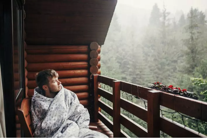 Man wrapped in blanket on porch