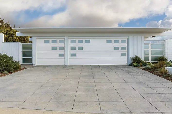 A mid-century modern home with a garage door that includes a geometric design for modern curb appeal
