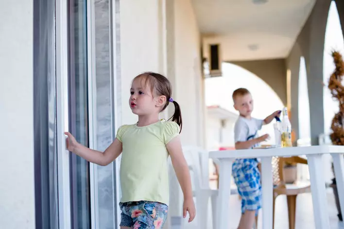 A little girl walking back inside from playing with her brother through their easy-to-use sliding patio doors.