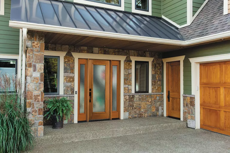 A woodgrain, full lite front door and sidelites on a green house.