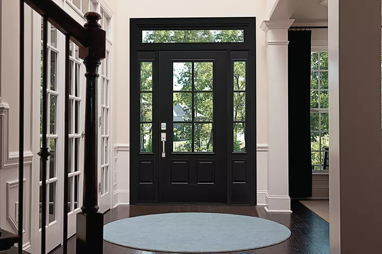 Black entry door with grids, sidelites, and a transom window inside a white foyer.