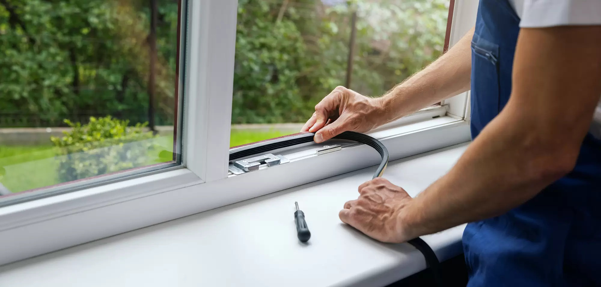 Worker applying weatherstripping to the bottom of a window.