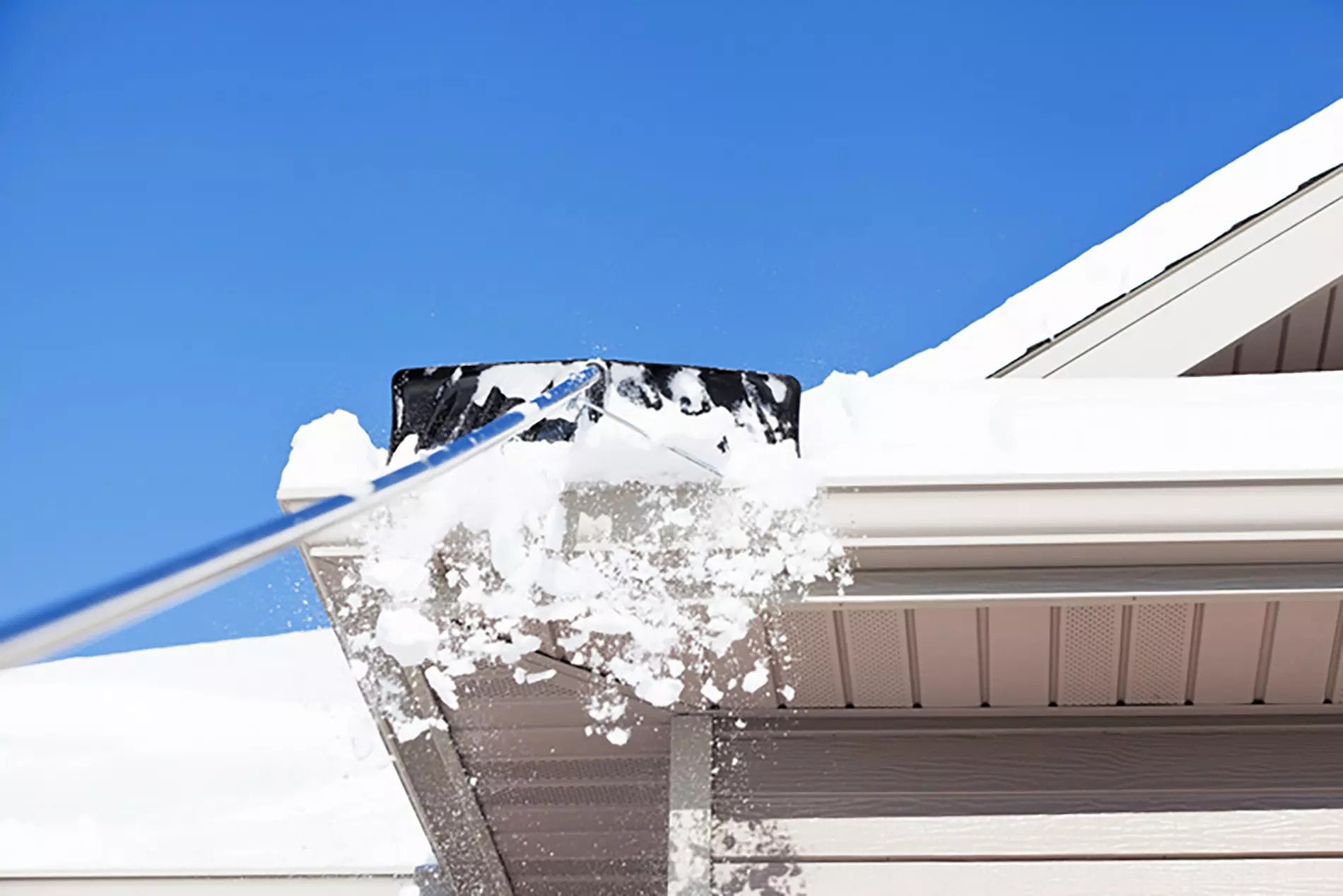 An image showing the process of raking snow off a roof.