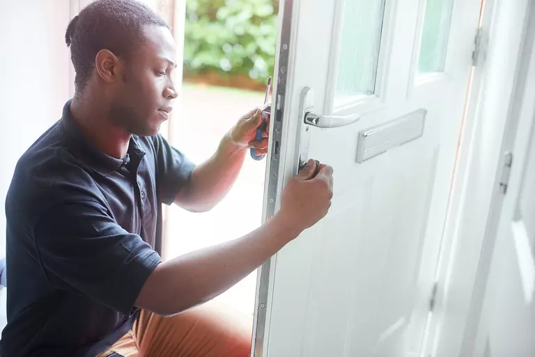 An expert easily and efficiently installing a new front door onto a home.