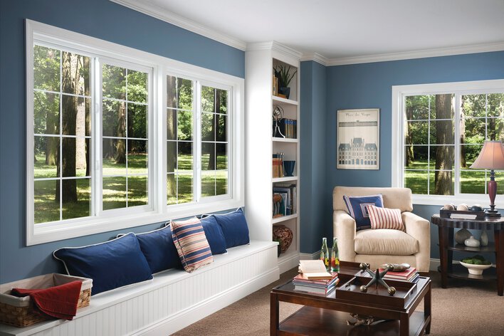 Bedroom of a home with blue-colored walls and an array of custom sliding windows.