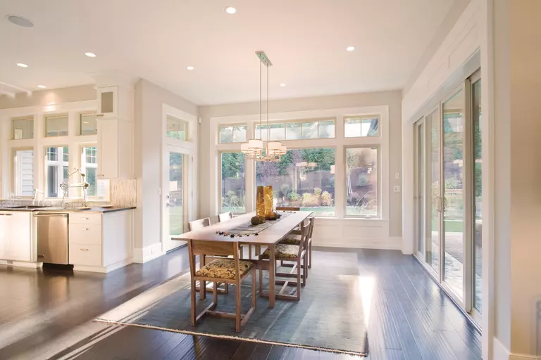 A renovated dining room with new hardwood floors and a large picture window.