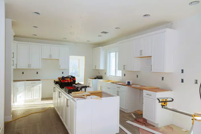 A kitchen with a central island and white cupboards in the middle of a renovation.
Kitchen renovations can breathe new life into an older home.