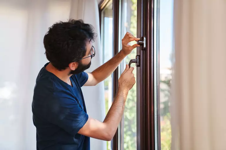 Man inspecting the hardware on the side of a casement window.