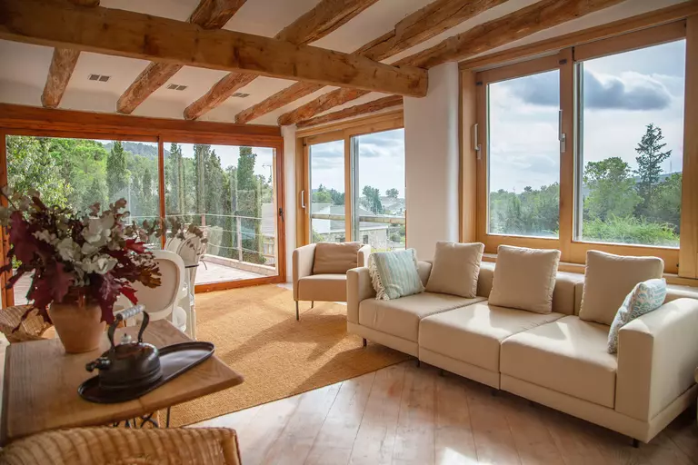 Upper living room view onto the garden, pool, and courtyard of a Spanish farmhouse
with large windows