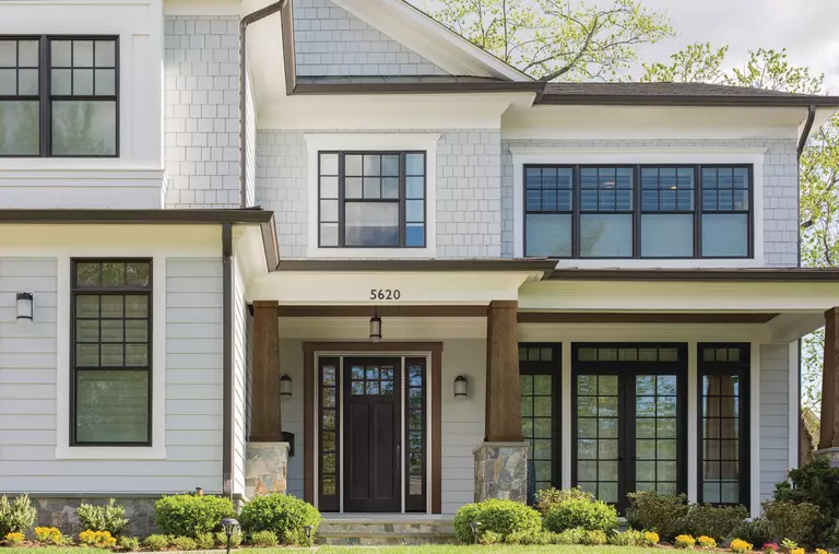The dark brown front door of a large white home.
