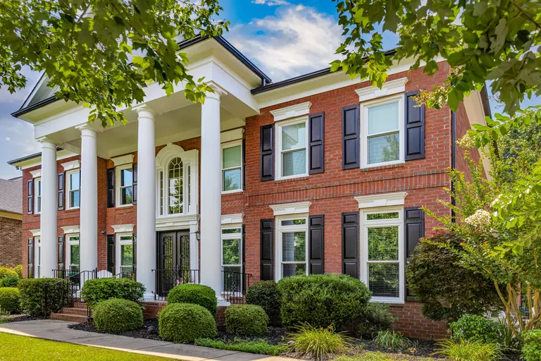 Two-story home with a brick exterior, white double-hung windows, and black shutters.