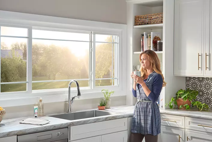 Woman enjoys morning sun from her kitchen window