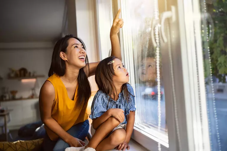 Woman with her child looking up through a sunny window.