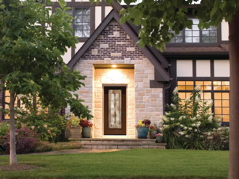 A new entry door installed on a large home with wood and brown accents to enhance curb appeal.