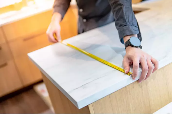 A person measuring a countertop in a kitchen