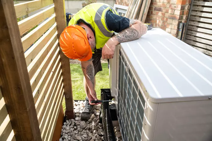 Man with a hard hat inspecting the heating system of a home.