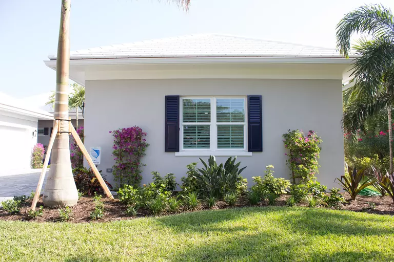 Black stylish shutters around the window of a stucco home to boost curb appeal.