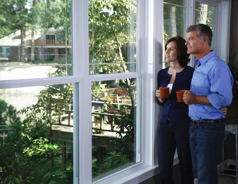 A couple standing beside a row of double-hung windows.