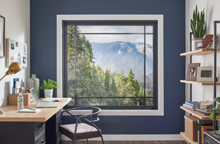 Inside of a home office with a large square picture window and a mountainside view.