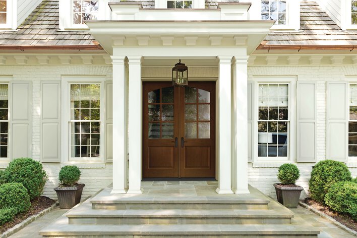 Classic mahogany entry door installed on a beautiful white home.