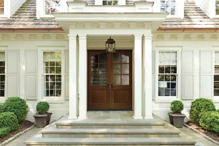 Classic mahogany entry door installed on a beautiful white home.