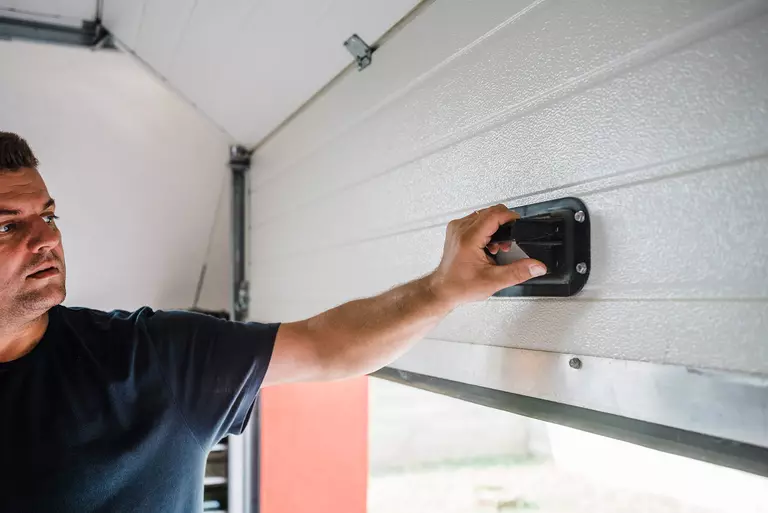 Man partially opening a garage door to test its balance.