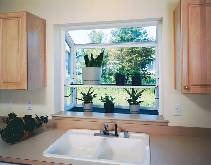 A garden window with potted plants above a sink
