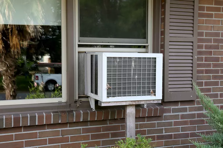Window air conditioner system installed on a brick house.