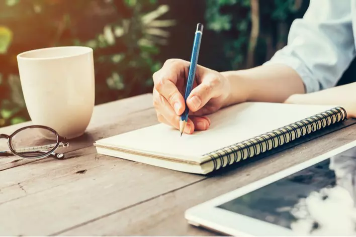 A person creating a home remodeling budget in a notebook