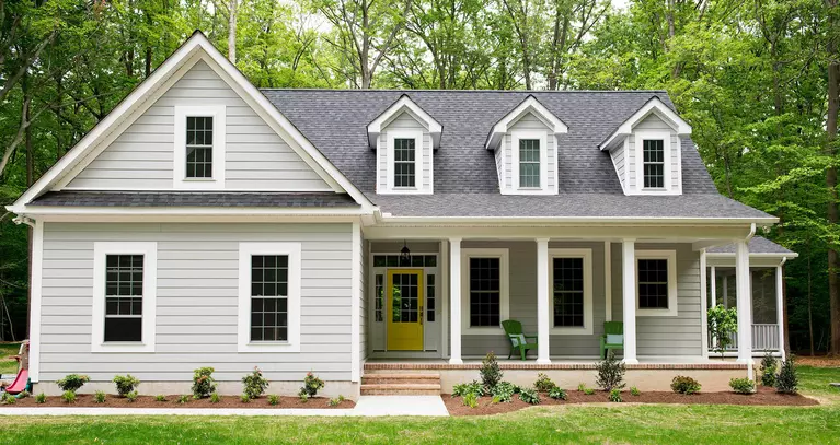 A home with off-white siding, multiple double-hung windows, and a yellow front door.