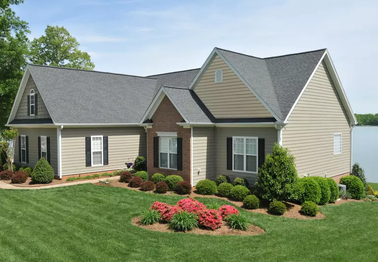 A vinyl siding home on the lake with a large front yard, landscaping, and energy-efficient windows.