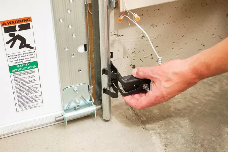Person adjusting a garage door sensor.