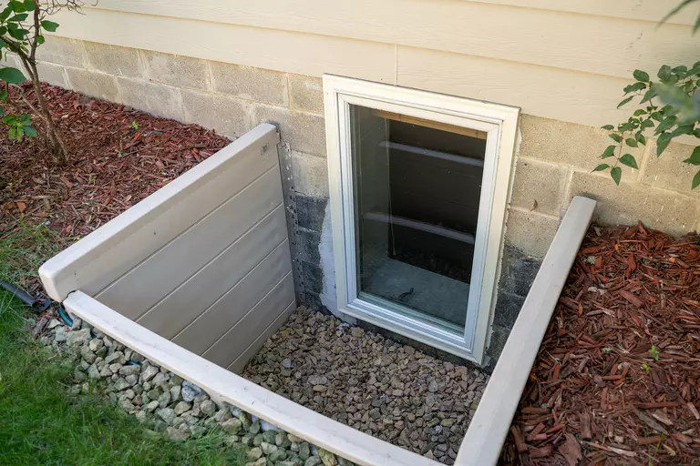 An egress basement window of a home that allows for natural light and an exit route in case of emergencies.
