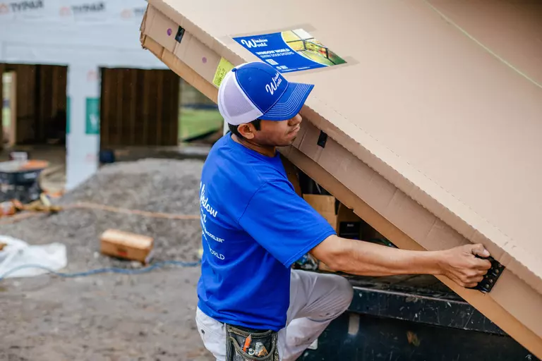 Window World worker lifting a box of garage door materials and insulation.